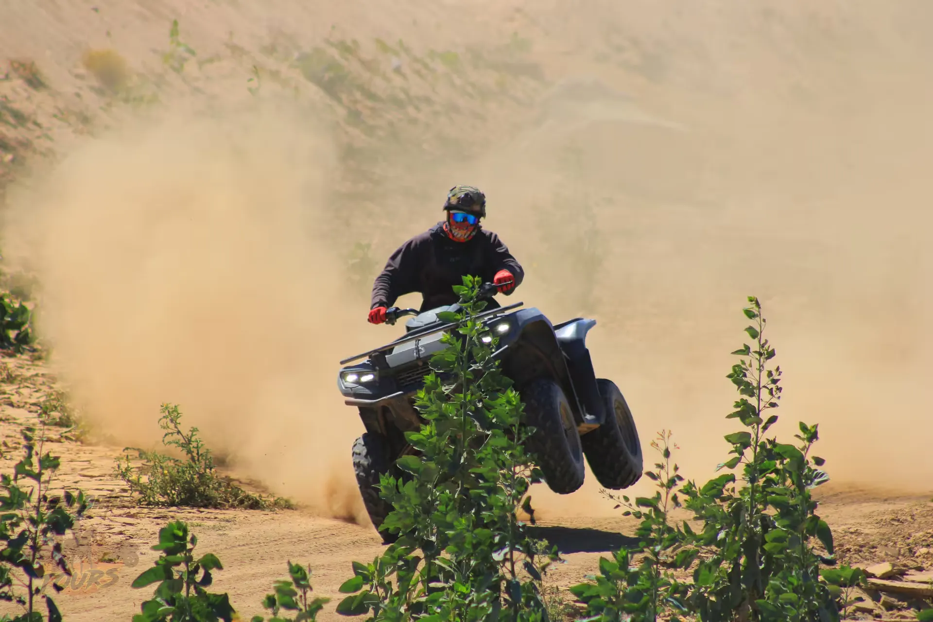 ATV rider kicks up dust on desert trail in Baja California Sur with green vegetation