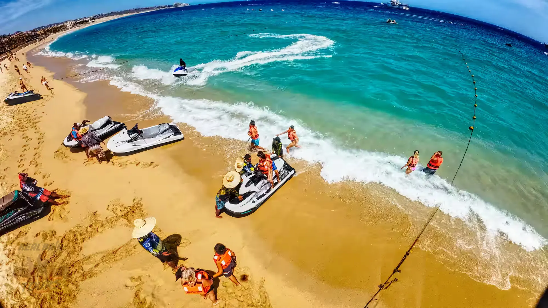 Aerial view of tourists enjoying water sports and swimming at a playa de arena in Baja California Sur with jet skis and clear turquoise waters