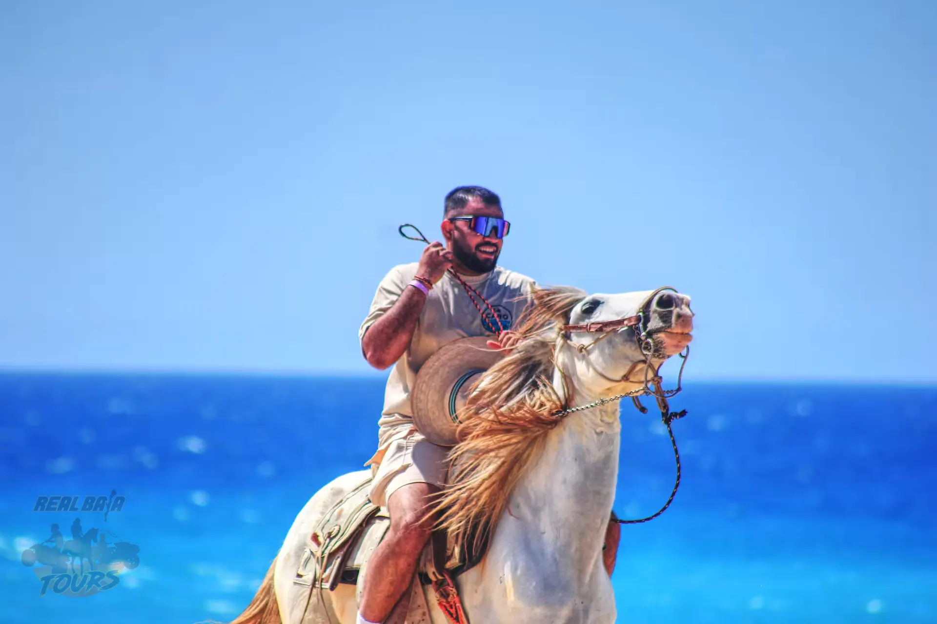 Man riding a camel along the beach in Baja California Sur with ocean backdrop Man riding a camel along the beach in Baja California Sur with ocean backdrop
