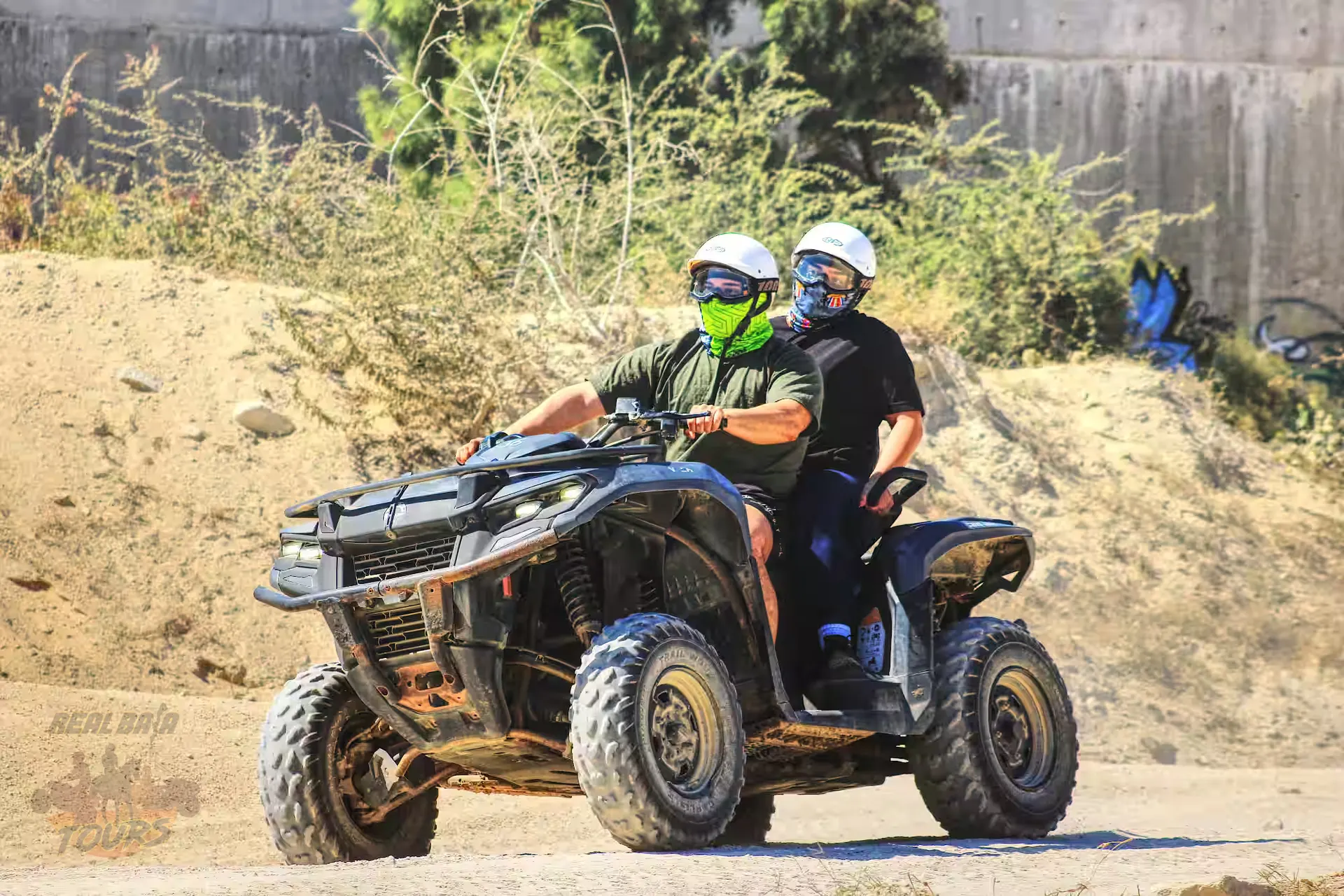 Two jinetes en an ATV in Baja California Sur desert with sandy terrain and vegetation