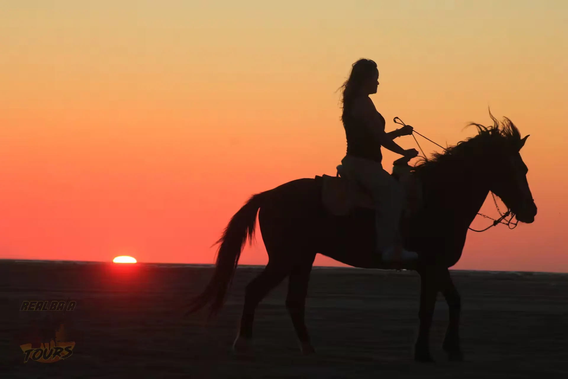 Silhouette of woman riding horse on beach at sunset in Baja California Sur