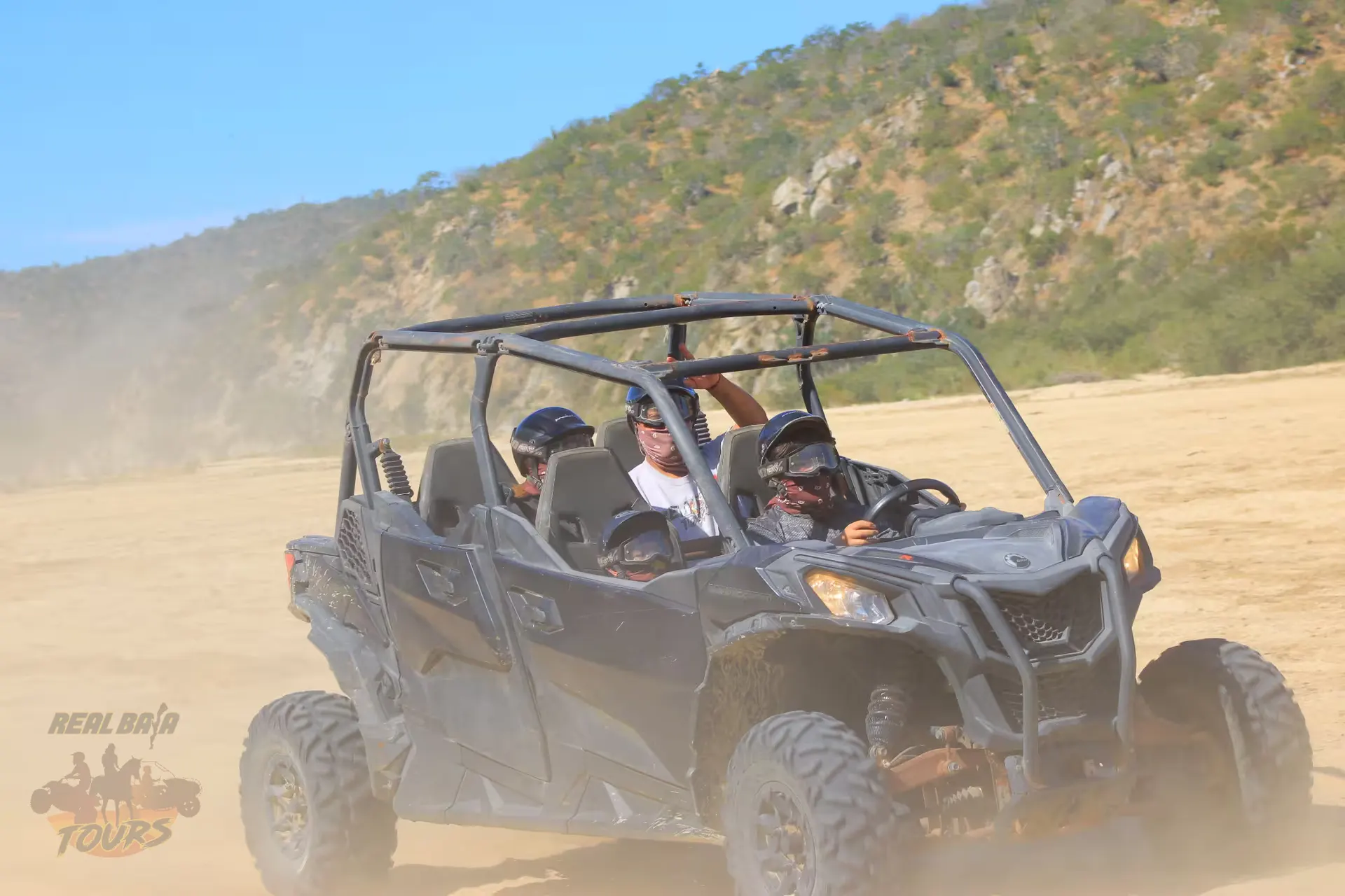 Four passengers enjoying an exhilarating UTV tour through dusty desert terrain with rocky mountains in Baja California Sur