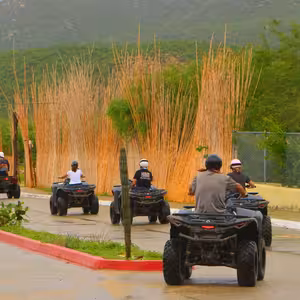 Group of tourists riding ATVs on a desert trail tour in Baja California Sur with cacti and mountains in background