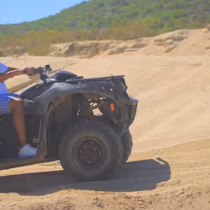 ATV rider wearing a helmet and mask driving through sand dunes