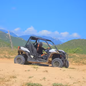 UTV driving through desert scrubland with mountain views