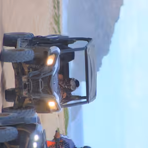 UTV and ATV riding along the coast at dusk with headlights on