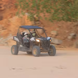 UTV driving along a rocky desert trail in warm evening light