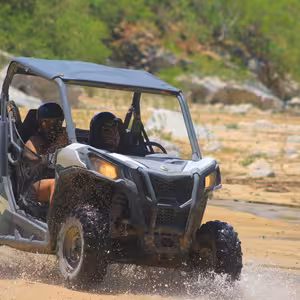 UTV splashing through a puddle on a rocky desert trail