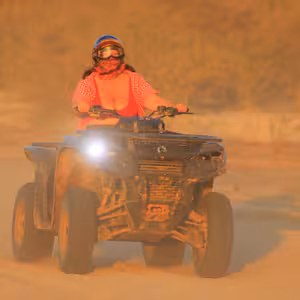 ATV rider driving through golden dust at sunset