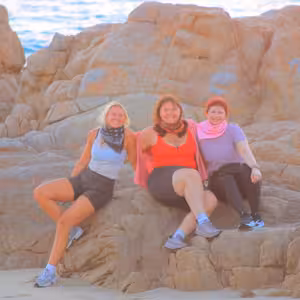 Three friends posing on a rock formation by the ocean