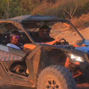 Close-up of a Can-Am Maverick X3 buggy driving through the desert at sunset