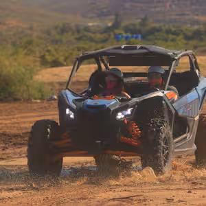 Can-Am X3 splashing through a muddy puddle on a desert trail