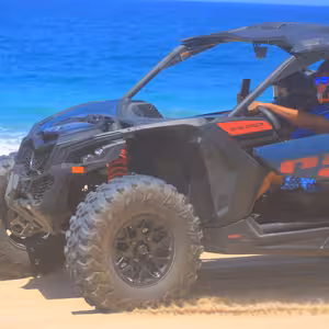 Can-Am Maverick X3 buggy driving along a beach with turquoise water