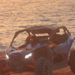Can-Am X3 buggy driving along the beach at sunset