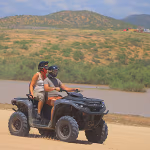 ATV crossing a shallow river with storm clouds in the distance