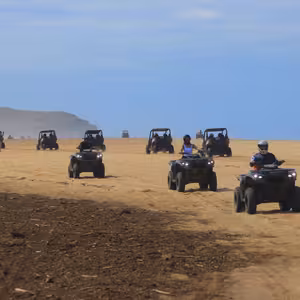 A convoy of ATVs and UTVs riding along the beach