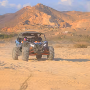 Can-Am X3 Turbo kicking up dust with dramatic desert mountains behind it near Cabo San Lucas