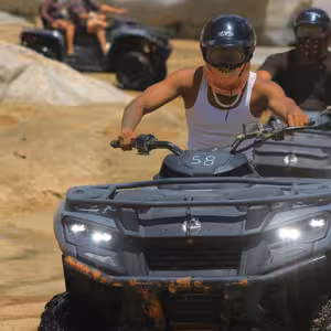 Group of ATV riders with headlights on riding through a rocky canyon