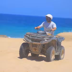 Solo ATV rider on a sandy beach near Migrino with vivid turquoise ocean water and breaking waves behind him