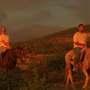 Two horseback riders on a desert hillside bathed in dramatic red and orange sunset light