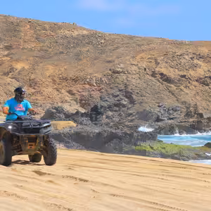ATV rider along a rocky turquoise coastline near Migrino Beach