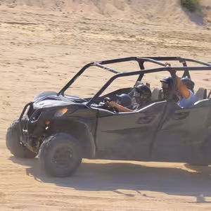 Four riders in a UTV kicking up dust on a desert trail near Cabo San Lucas