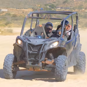 Four riders in a UTV along a coastal cliff overlooking turquoise ocean
