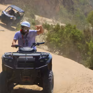 ATV rider on sandy desert trail with rocky cliffs and vegetation in Baja California Sur