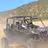 Four passengers enjoying an exhilarating UTV tour through dusty desert terrain with rocky mountains in Baja California Sur