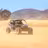 Blue and black UTV levantando polvo while driving across a sandy desert valley with mountains in Baja California Sur