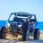 Blue and orange dune buggy with two passengers on a playa de arena with turquoise ocean and clear sky in Baja California Sur